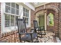 Inviting front porch with rocking chairs, brick arch, and tiled flooring at 1718 Ridgewood Ne Dr, Atlanta, GA 30307