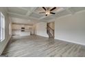 Open-concept living area with hardwood floors, coffered ceiling, staircase and kitchen with island at 402 Westmarch Cir # 285A, Loganville, GA 30052