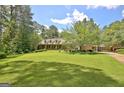 Stunning brick home with a lush, green lawn, mature trees, and rocking chair front porch at 115 Shoal Creek Dr, Sharpsburg, GA 30277