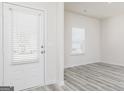 Bright entryway with a white door, gray wood-look floors, and natural light streaming through the window at 448 Prescott Way, Villa Rica, GA 30180