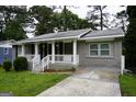 Inviting grey brick home with a covered front porch featuring white railing and a well-kept yard at 39 Mcferrin Cir, Riverdale, GA 30274