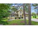 View of a charming two-story home with an attached two-car garage framed by mature trees at 115 Rockhurst Chase, Tyrone, GA 30290