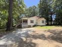 Serene single-story home with a red roof, surrounded by mature trees and a natural landscape with gravel driveway at 2306 Old Lower River Rd, Douglasville, GA 30135