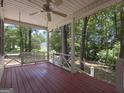 Inviting porch with a ceiling fan and a charming porch swing, offering a relaxing outdoor space among trees at 2306 Old Lower River Rd, Douglasville, GA 30135