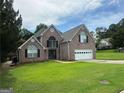 Beautiful two-story brick home with a manicured lawn, double-door entry, and attached two-car garage at 12189 Lauren Way, Fayetteville, GA 30215