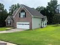 Well-maintained two-story brick home with a two-car garage and lush green lawn with mature trees at 12189 Lauren Way, Fayetteville, GA 30215