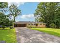 Lovely one-story home with a brick facade, carport, and a spacious front yard showcasing mature trees at 3212 Georgian Woods Cir, Decatur, GA 30034