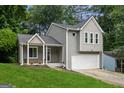 Charming two-story home with gray siding, attached garage, manicured lawn, and lovely front porch with flower accents at 2069 Countydown Ln, Stone Mountain, GA 30088
