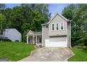 Charming two-story home with gray siding, attached garage, manicured lawn, and lovely front porch with flower accents at 2069 Countydown Ln, Stone Mountain, GA 30088