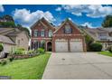 Charming two-story brick home featuring a two-car garage, and a lush green lawn at 705 Lawton Bridge Sw Rd, Smyrna, GA 30082