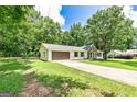 Wide angle view of the home featuring a long driveway leading to the two-car garage and a well-maintained lawn at 125 Selena Ct, Fayetteville, GA 30215