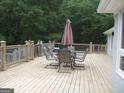 View of outdoor back deck with a dining table set and wooded background at 1455 River Cove Rd, Social Circle, GA 30025