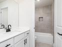 Bright bathroom featuring a bathtub and shower combo with gray tiled walls and modern fixtures at 676 Cantrell Drive, Dallas, GA 30157