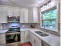 Well-appointed kitchen featuring white cabinets, stainless appliances, tile backsplash, and quartz countertops at 4579 S Amberly S Ct, Atlanta, GA 30360