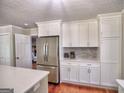 Spacious kitchen featuring stainless steel refrigerator, modern white cabinets, and quartz countertops at 4579 S Amberly S Ct, Atlanta, GA 30360