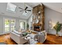 Inviting living room showcasing a stone fireplace, vaulted ceiling, skylights, and hardwood flooring at 103 Sandtrap Rdg, Peachtree City, GA 30269