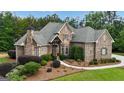 Inviting home exterior with stone and brick, complemented by green lawn and landscaping at 185 Platinum Ridge Pt, Fayetteville, GA 30215