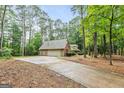View of the home with a long driveway leading to a detached garage in a wooded setting at 215 Longwood Dr, Jonesboro, GA 30236