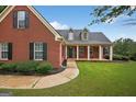 Close-up of a red brick home with a covered front porch, showcasing its well-maintained landscaping and inviting entrance at 65 Pecan Ln, Oxford, GA 30054