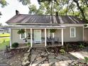 Inviting front porch with chairs, plants, and a light green door, and stone walkway at 6192 Collins Ne St, Covington, GA 30014