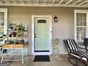 Charming covered front porch with comfortable seating and decorative plants near a light green door at 6192 Collins Ne St, Covington, GA 30014