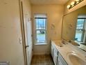 Well-lit bathroom with dual sinks, a large mirror, and a view from the window at 6367 Ellenwood Drive, Rex, GA 30273