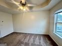 Bedroom featuring a tray ceiling with a ceiling fan, carpet flooring, and a window at 6367 Ellenwood Drive, Rex, GA 30273