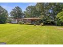 Charming ranch-style home with a red metal roof, inviting front porch, and lush, green lawn at 6674 Cowan Mill Rd, Winston, GA 30187