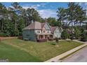 Beautiful two-story home featuring manicured lawn, stone accents, teal siding, and mature trees in a serene neighborhood setting at 125 Seawright Dr, Fayetteville, GA 30215