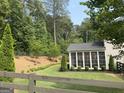 Backyard view of the sunroom, set in a serene landscape featuring mature trees and manicured landscaping at 6660 Canyon Cv, Cumming, GA 30028