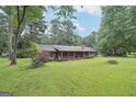 Well-maintained home with a sprawling lawn, covered porch, and mature trees providing ample shade at 5618 Shadow Rock Dr, Lithonia, GA 30058