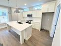 Modern kitchen with white cabinets, stainless steel appliances, and an island with a sink and sleek countertops at 485 West Ave, Bowdon, GA 30108