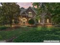 Charming stone home featuring a lush front yard with mature trees and manicured landscaping at twilight at 914 Champions Way, Mcdonough, GA 30252