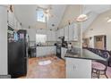 Bright kitchen featuring vaulted ceilings, white cabinetry, black appliances, and a breakfast bar with seating at 603 Rossie Court, Mcdonough, GA 30252