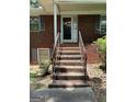 Brick steps lead to a covered porch and front door, framed by iron railings and greenery at 5277 Scofield Rd, South Fulton, GA 30349