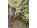 Spacious covered front porch with stone flooring, supported by white columns and black iron railings at 5277 Scofield Rd, South Fulton, GA 30349