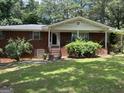 Classic red brick home with front porch, surrounded by mature trees and landscaped bushes at 5277 Scofield Rd, South Fulton, GA 30349