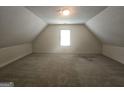 Spacious, carpeted attic with a single window, offering potential for storage or customization at 4680 Duval Point Sw Way, Snellville, GA 30039