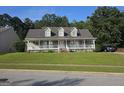 Inviting home features a covered front porch, lush green lawn, and mature trees, creating a serene setting at 4680 Duval Point Sw Way, Snellville, GA 30039