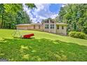 Beautiful view of the back of the house with a well-maintained lawn, mature trees, and unique garden accents at 351 Weldon Rd, Palmetto, GA 30268