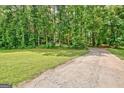 Gravel driveway leading to a property surrounded by lush trees and greenery at 351 Weldon Rd, Palmetto, GA 30268