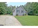 Side view showing a gray house with a well-kept lawn and driveway, with a partial view of the garage at 85 Holly Springs Rd, Sharpsburg, GA 30277