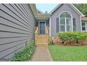 Close-up of front entrance with wooden steps and landscaping; the home features gray siding at 85 Holly Springs Rd, Sharpsburg, GA 30277