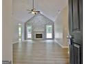 Living room with stone fireplace, high ceilings, ceiling fan, wood flooring, and backyard access at 85 Holly Springs Rd, Sharpsburg, GA 30277