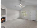 Spacious living room with a fireplace, neutral carpet, ceiling fan, and ample natural light at 120 Bramble Bush Trl, Covington, GA 30014