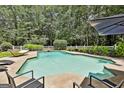 Gorgeous swimming pool with a seating area surrounded by a white fence and lush greenery at 140 Silvermere, Fayetteville, GA 30215