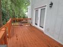 View of the bright orange wooden deck featuring a white railing and glass paneled doors at 2052 Charter Ln, Lithonia, GA 30058