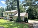 Two-story home with stone accents, surrounded by mature trees and greenery, offering a peaceful suburban setting at 3589 Burlingham Dr, Lithonia, GA 30038