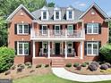 Stunning two-story brick home features a balcony, black shutters and lush landscaping at 100 Castlebrook Chase, Tyrone, GA 30290