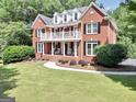 Spacious two-story red brick home with a balcony, complemented by a well-manicured front lawn at 100 Castlebrook Chase, Tyrone, GA 30290